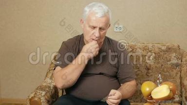 生病的超重老人在家里沙发上吃药丸，在玻璃杯里喝水。 他制造了几种光滑的液体